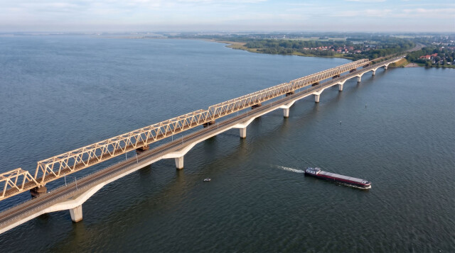 Een binnenvaartschip vaart onder de spoorbruggen op het Hollands diep
